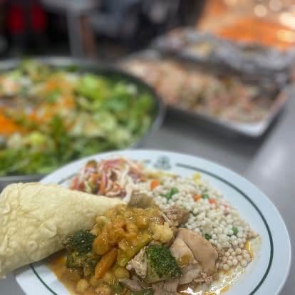 A plated Chef Skills meal — chicken curry with couscous, vegetables, salad and a wrap.