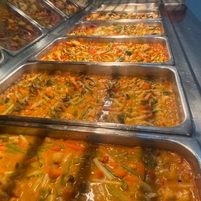 Bain-marie trays of curries and saucy vegetable mains ready to serve.