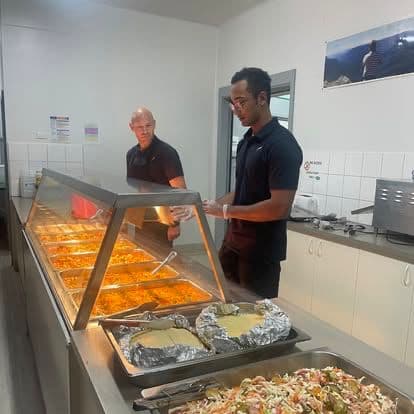 Chef Skills team working a buffet line of curries and roasted mains.